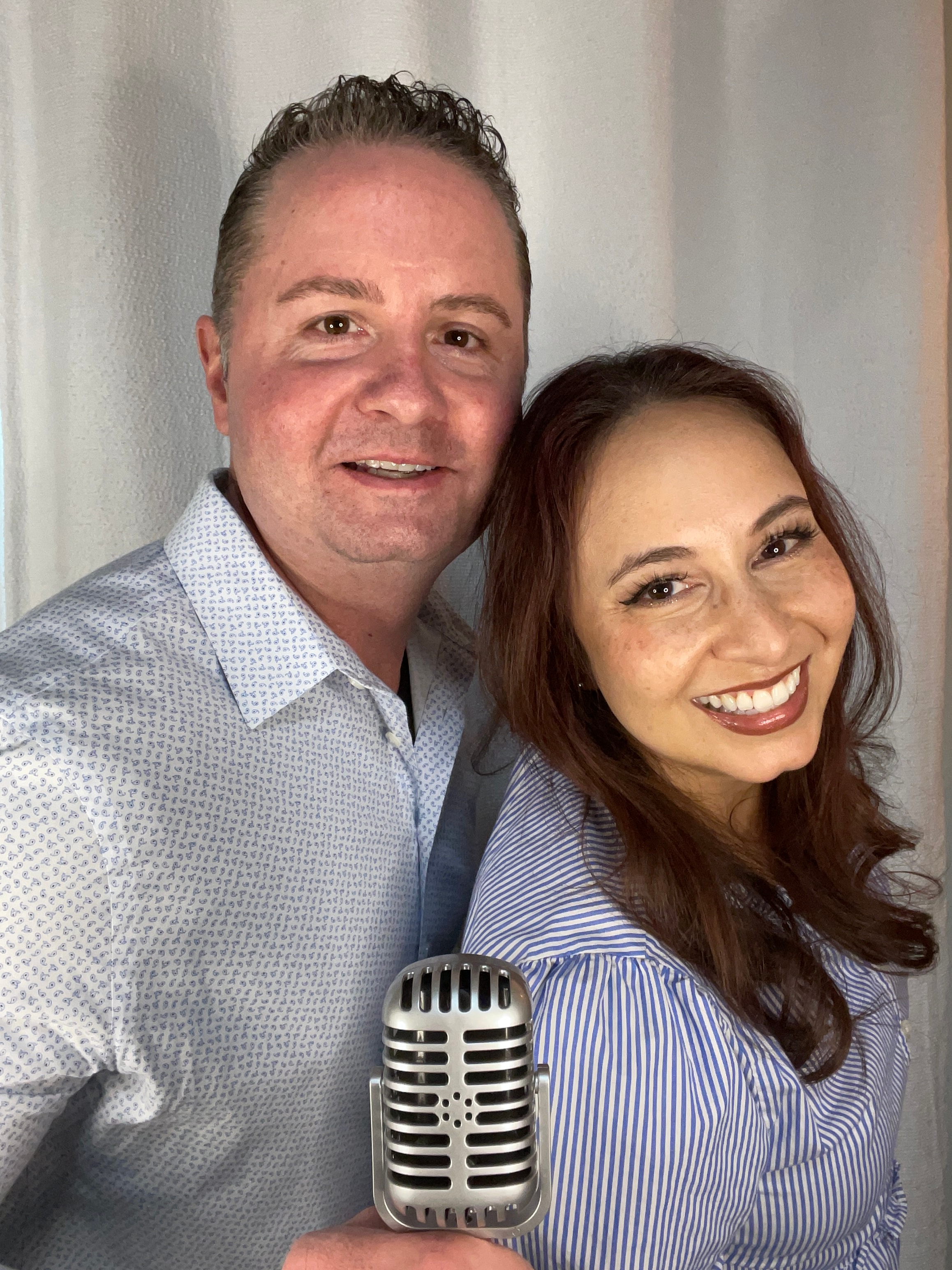 Brandon and Tina James smiling together holding a vintage microphone